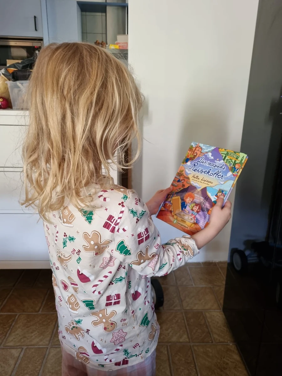 Kind liest im Buch Der magische Reisekoffer