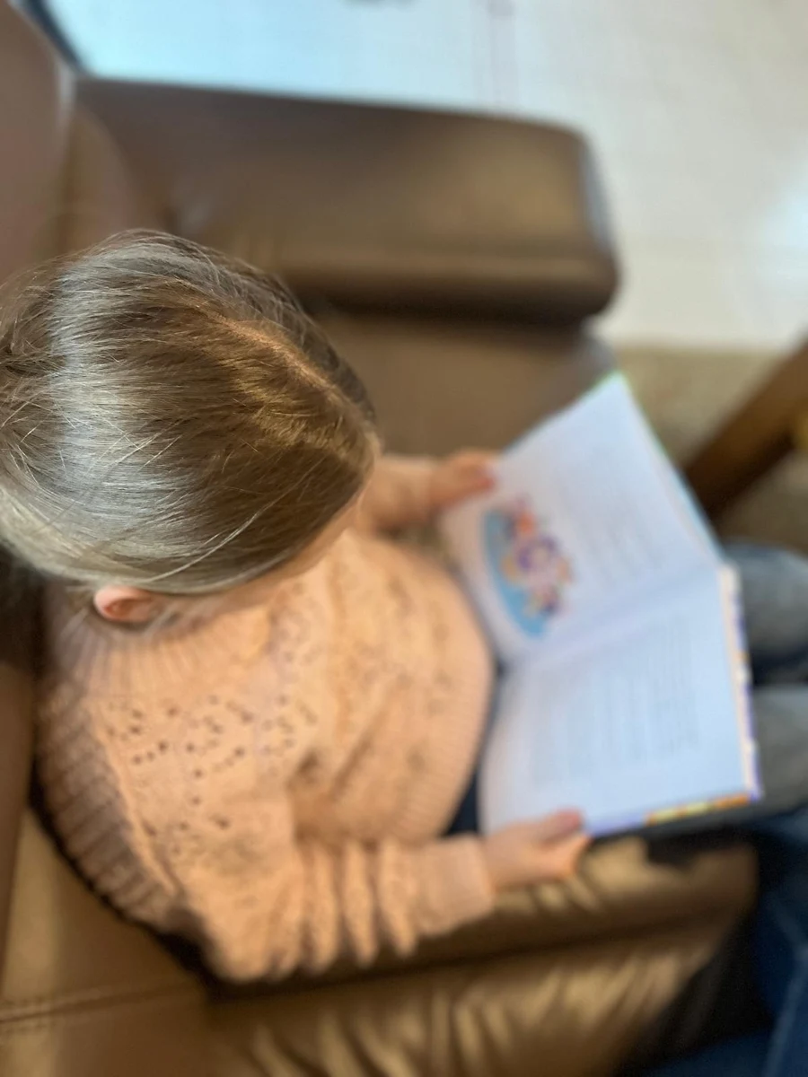 Kind liest im Sessel im Buch Der magische Reisekoffer